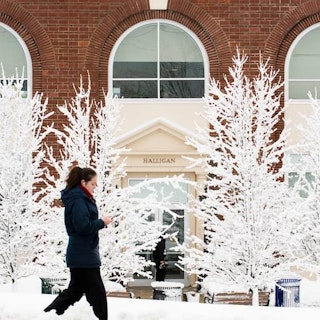 A student walks across campus in winter.